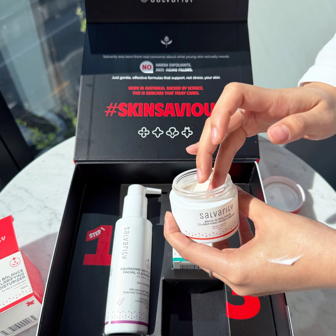 Person applying skincare cream from a jar with 'Salvarity' branding, surrounded by other skincare products and packaging.