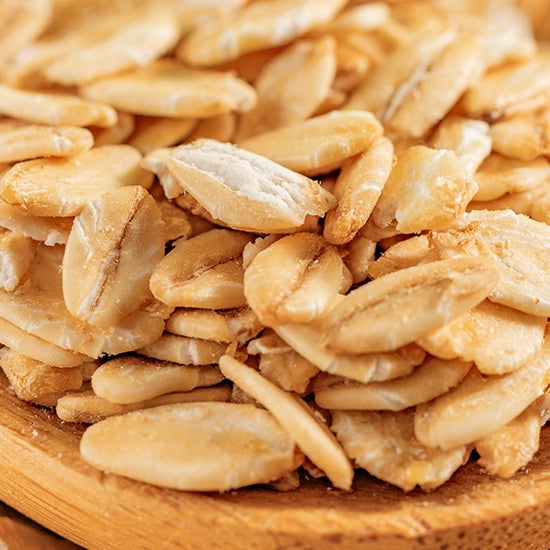 Close-up image of dry rolled oats on a wooden surface used for skincare